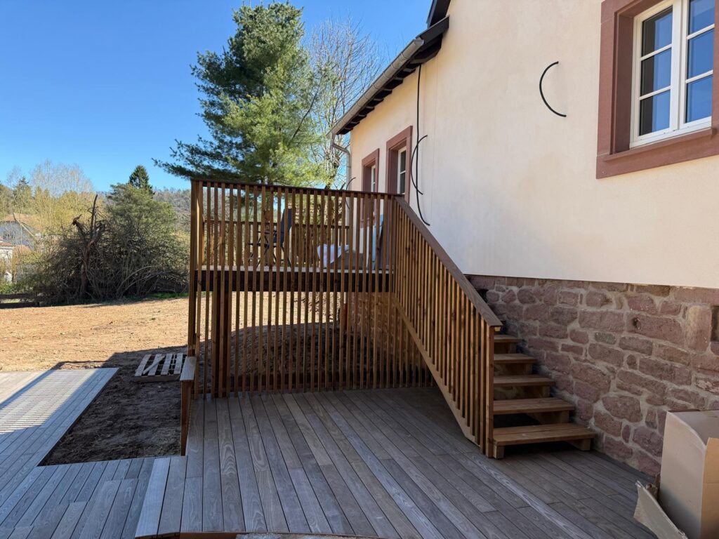 Terrasse surélevée en thermofrêne avec garde-corps en pin à balustres et escalier en bois massif